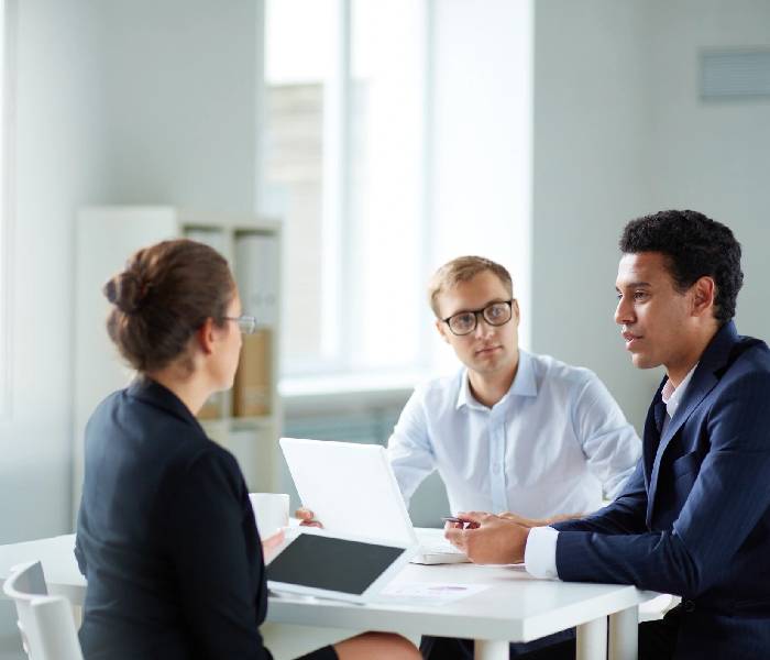 Three people sitting at a table with papers and laptops.