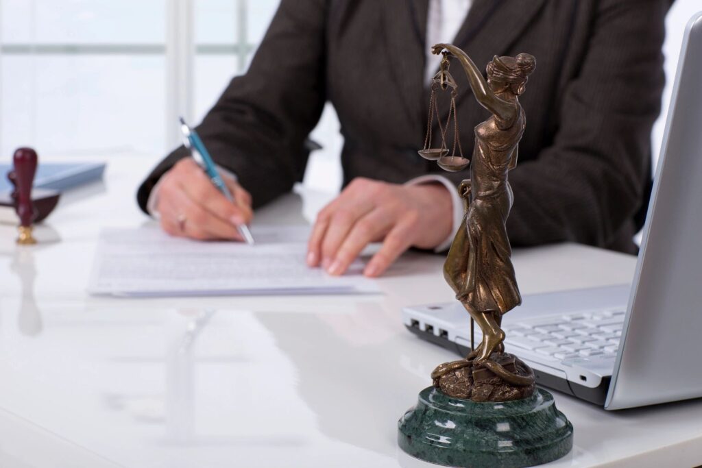 Justice statue on desk with person writing.